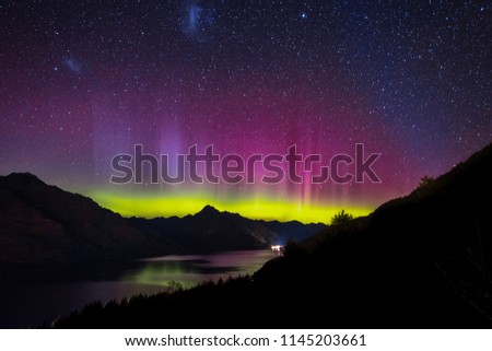 Spectacular view as aurora lights up the sky of Queenstown, New Zealand. When particles from a solar storm reached our Earth, it creates an array of colored lights as they hit the atmosphere. Royalty-Free Stock Photo #1145203661