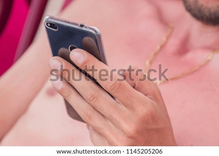 young man sitting in lounger chair and checking messages on his smartphone, freelance concept