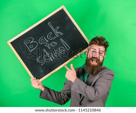 Teacher bearded man holds blackboard with inscription back to school green background. Invite to celebrate day of knowledge. Teacher happy cheerful congratulates with beginning new school year.