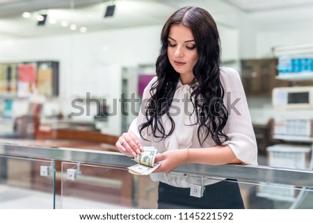 Attractive brunette with dollar banknotes in big mall