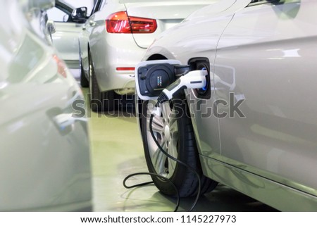 Close up of the Hybrid car electric charger station with power supply plugged into an electric car being charged.	