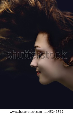 fashion portrait of beautiful girl peering behind the glass,young woman face profile under the water,creative idea, the concept of uniqueness, beauty and style