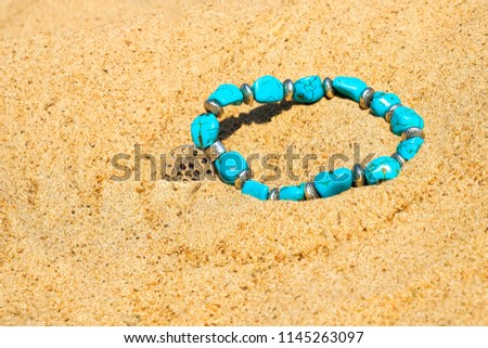 Beautiful semi-precious stone beads on the sea sand.