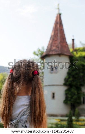 A cute girl looking at the tower of fairy castle and dreaming about charming prince, dream of childhood, summer outdoor portrait
