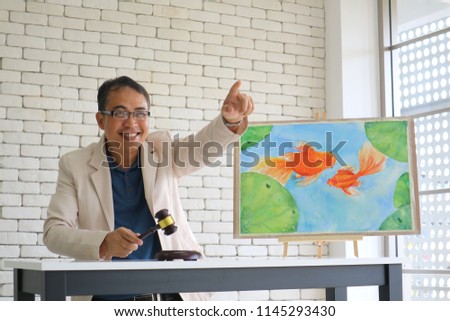 The business man auctioning beautiful fish's picture with wooden hammer

