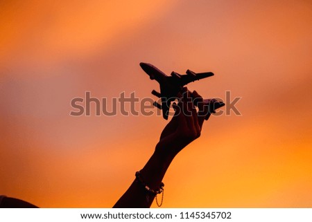 Silhouette of an airplane in the hand on the background of the setting sun