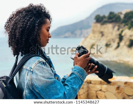 Woman taking a picture of a sea landscape with a professional camera