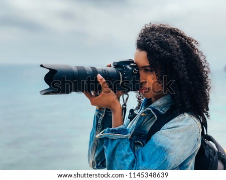 Woman taking a picture of a sea landscape with a professional camera