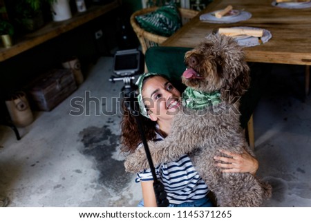 young beautiful woman taking a selfie with her spanish water dog in a cafe. Daytime, love for animals concept and lifestyle