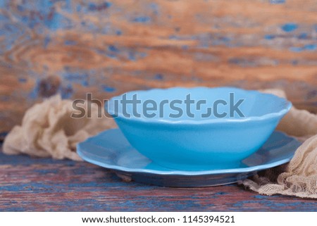 Blue round plate and bowl on brown background of wooden table