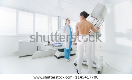 In the Hospital, Mammography Technologist / Doctor adjusts Mammogram Machine for a Female Patient. Friendly Doctor Explains Importance of Breast Cancer Prevention Screening.