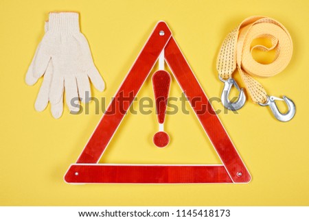 top view of warning triangle road sign, gloves and car tow rope isolated on yellow