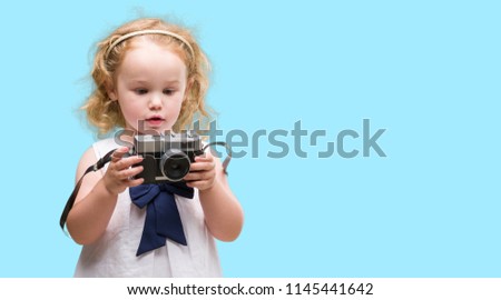 Beautiful blonde toddler taking pictures with vintage camera