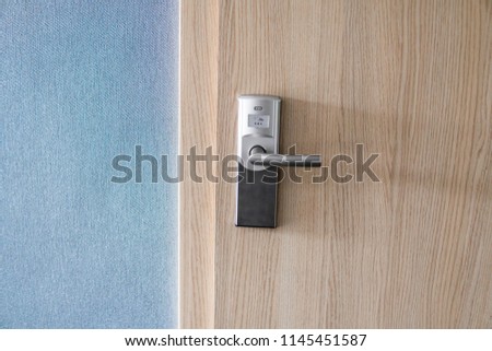 Hotel electronic lock on wooden door and with a blue wall.