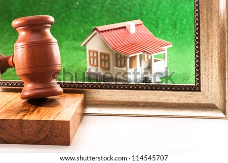 Auction hammer, frame and the house on a green background