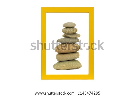 Stone stack in a yellow  picture frame isolated on white background