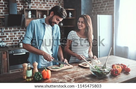 Romantic couple is cooking on kitchen. Handsome man and attractive young woman are having fun together while making salad. Healthy lifestyle concept. Royalty-Free Stock Photo #1145475803