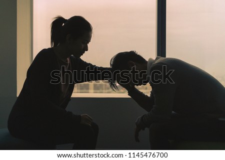 PTSD Mental health concept, Young depressed asian man talking with psychologist sitting near window in dark room at evening time with low light environment.Selective focus. Royalty-Free Stock Photo #1145476700