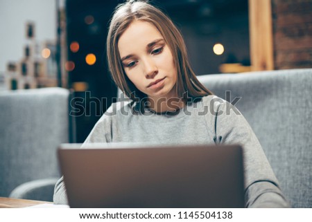 Young beautiful woman is using laptop in a cafe.