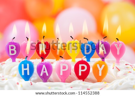 Happy birthday written in lit candles on colorful background
