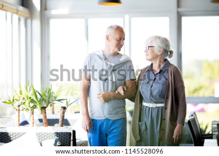 Portrait of loving senior couple posing hand in hand and looking at each other tenderly while standing in cafe