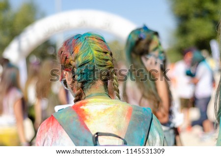 Girl is standing after Colorsky 5k run with her paint covered braids.