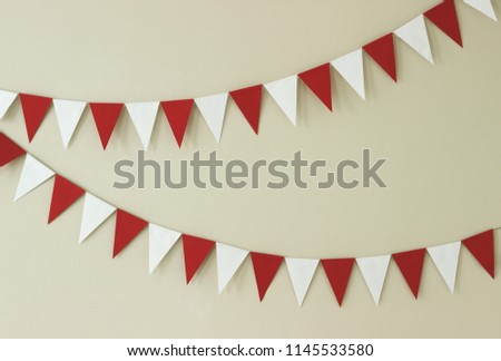 Triangular paper handmade garlands of white and red on a light wall.