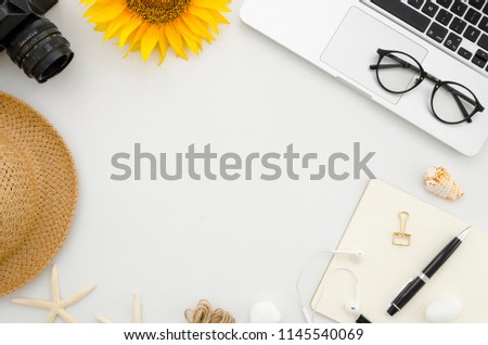 Flat lay mock up. Summer frame from office supplies on white office table with laptop, clips, glasses, notebook, pen, retro photo camera, hat, starfish, sunflower and headphones. Travel mood