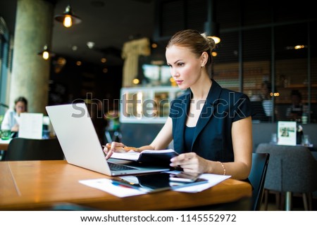 Adult woman business worker searching financial information on web site via laptop computer, sitting in restaurant. Female skilled entrepreneur checking online e-mail via netbook. Economist using apps