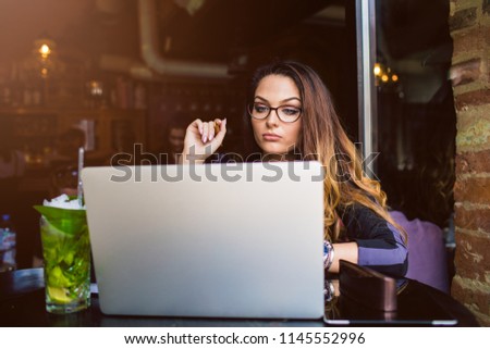 Serious woman successful business owner checking monthly reports on laptop computer during coffee break in restaurant. Concentrated female associate web editor reading information on site via netbook 