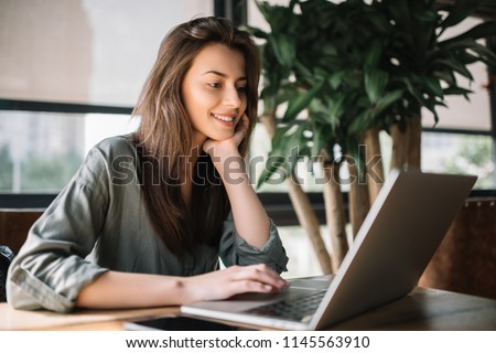 Successful freelancer typing on keyboard using laptop computer in loft office. Portrait of copywriter working online at workplace. Smiling student learning languages at library, planning project.  Royalty-Free Stock Photo #1145563910