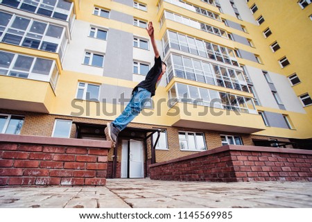 Teenage boy on a street in a big city next to a high-rise building alone. concept of a teenager parkour life. parkour jump on a high-rise building background