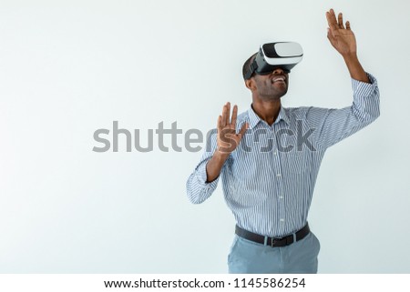 Try it in action. Cheerful smiling afro american man wearing VR glasses while standing against white background