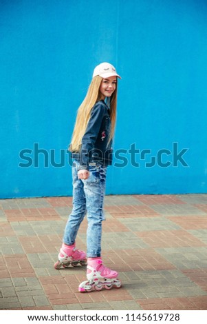 beautiful happy young girl riding roller skates in city