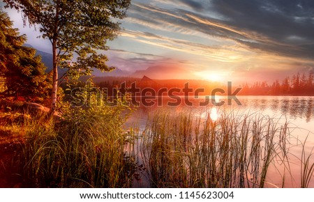 Colorful Autumn landscape under warm Sunlit. Amazing Mountain Lake Strbske Pleso at Sunset. beautiful summer scene with Colorful Sky. Picture of Wild area. Wonderful Picturesque Scene of nature  
