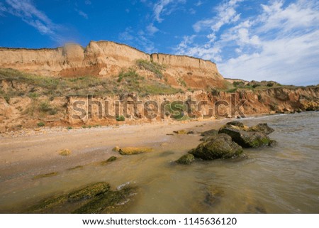 
sea ​​landscape with yellow mountains and cliffs against the blue sky and the sea, 
sunny summer day with blue sky and yellow rocks