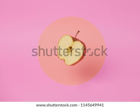 half apple levitate in air on pink background.