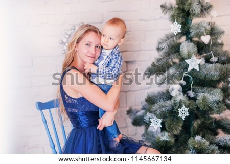 Christmas photo with mom and baby boy near the Christmas tree.