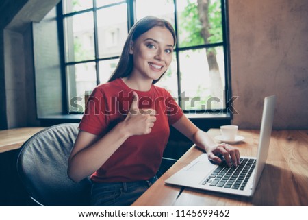 Portrait of beautiful, attractive girl freelancer showing thumbs up working remotely in cafe behind the laptop Royalty-Free Stock Photo #1145699462