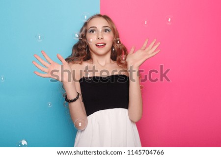 Beautiful young woman with soap bubbles over cyan background. Portrait of young beautiful girl in Studio, with professional makeup. Beauty shooting. The beauty of soap bubbles.