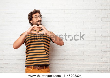 young dumb man smiling, looking happy and in love, making the shape of a heart with hands.