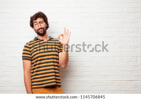 young dumb man making an "alright" or "okay" gesture approvingly with hand, looking happy and satisfied. Positive check sign.