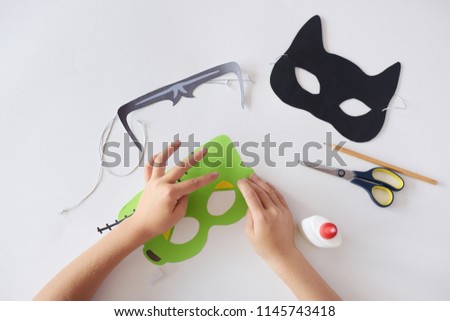 Making masks  paper  holiday Halloween Monster's  mask Black cat  Hands top view Scissors Glue