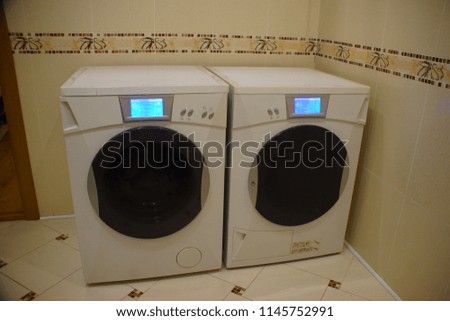Included white washing and drying machines with touch screens stand side by side.
