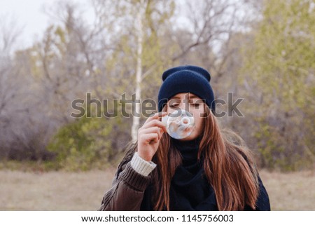 girl inflates large soap bubble in autumn