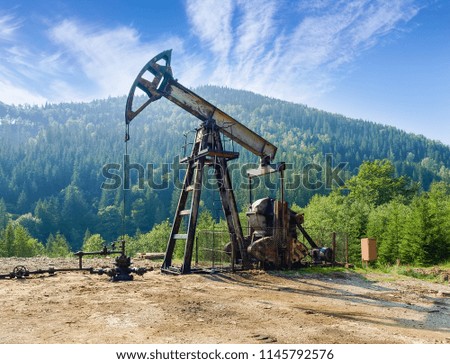 Pump-jack pumping petroleum on oil well located in the Carpathian Mountains 
