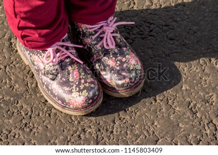 Pair of childs floral print boots on a grey background, isolated. Fashion for spring or autumn. Leather shoes for girl walking. Kids fashion for outside. Copy space