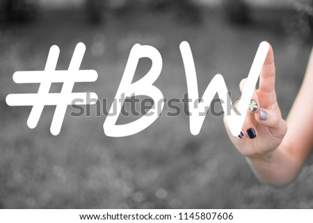  Hashtag  BW written with a female hand in the air.