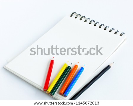Delightful image of an empty page of sketch book and a wooden  and colored pencils over a white background with a high angle view, leaving free space for message