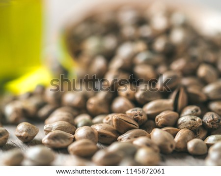 Close up view of hemp seeds and hemp oil on brown wooden table. Hemp seeds in wooden spoon and hemp essential oil in small glass bottle. Copy space for text. Shallow DOF Royalty-Free Stock Photo #1145872061